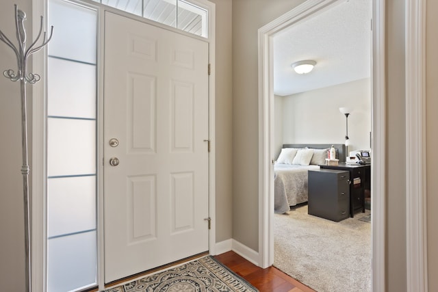 foyer with dark wood-type flooring, dark carpet, a textured ceiling, and baseboards