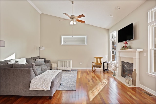 living area with hardwood / wood-style flooring, a fireplace, baseboards, and vaulted ceiling