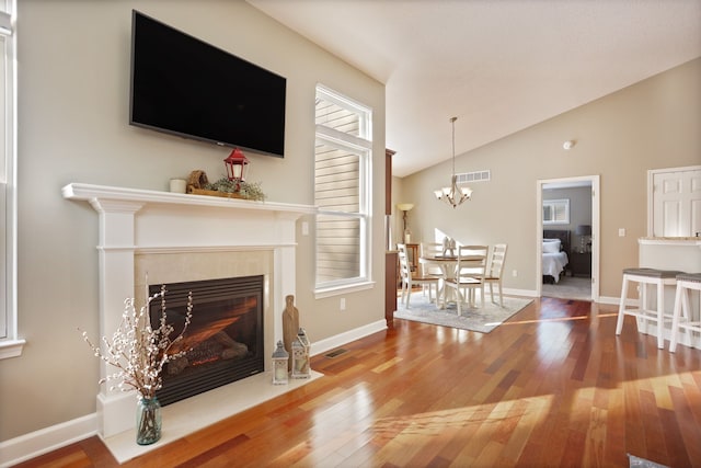 living area featuring visible vents, vaulted ceiling, a fireplace, and hardwood / wood-style flooring