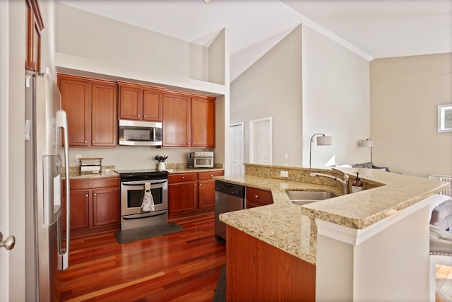 kitchen with light stone counters, dark wood finished floors, appliances with stainless steel finishes, a kitchen island with sink, and a sink