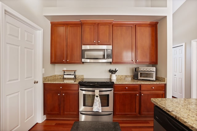 kitchen with appliances with stainless steel finishes, dark wood finished floors, and light stone countertops