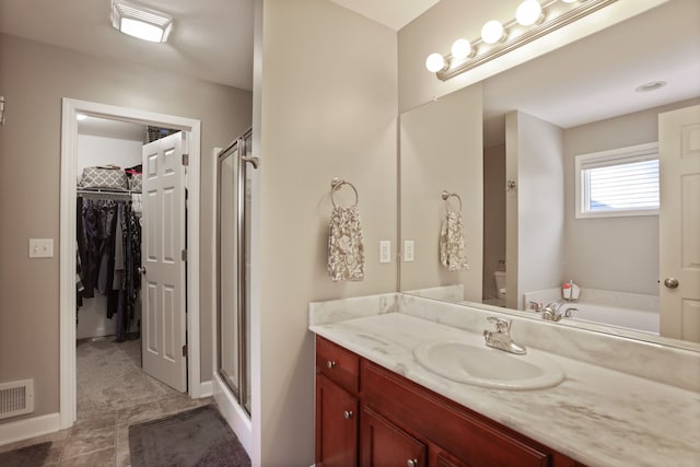 full bath with a stall shower, visible vents, a walk in closet, and vanity