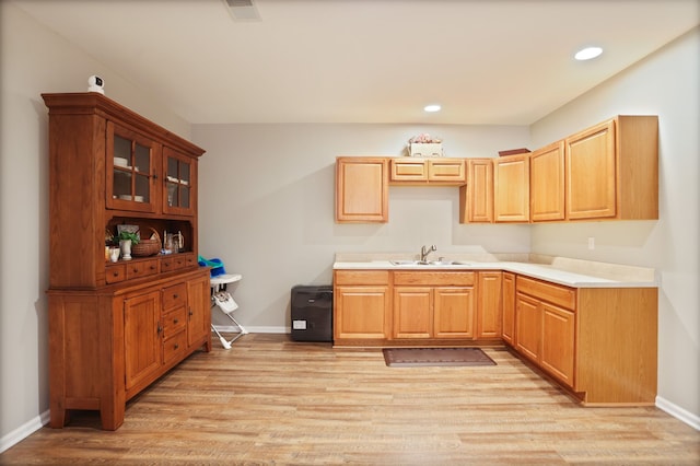 kitchen featuring recessed lighting, a sink, light wood-style flooring, and baseboards