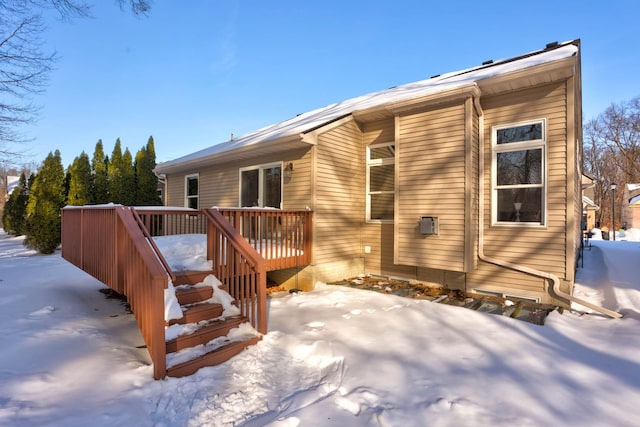 snow covered back of property featuring a wooden deck