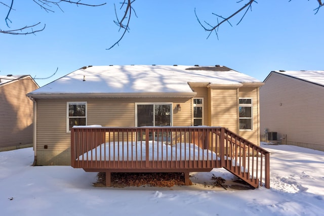 snow covered house with central air condition unit and a wooden deck