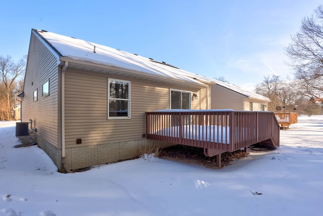 snow covered back of property featuring central AC and a wooden deck