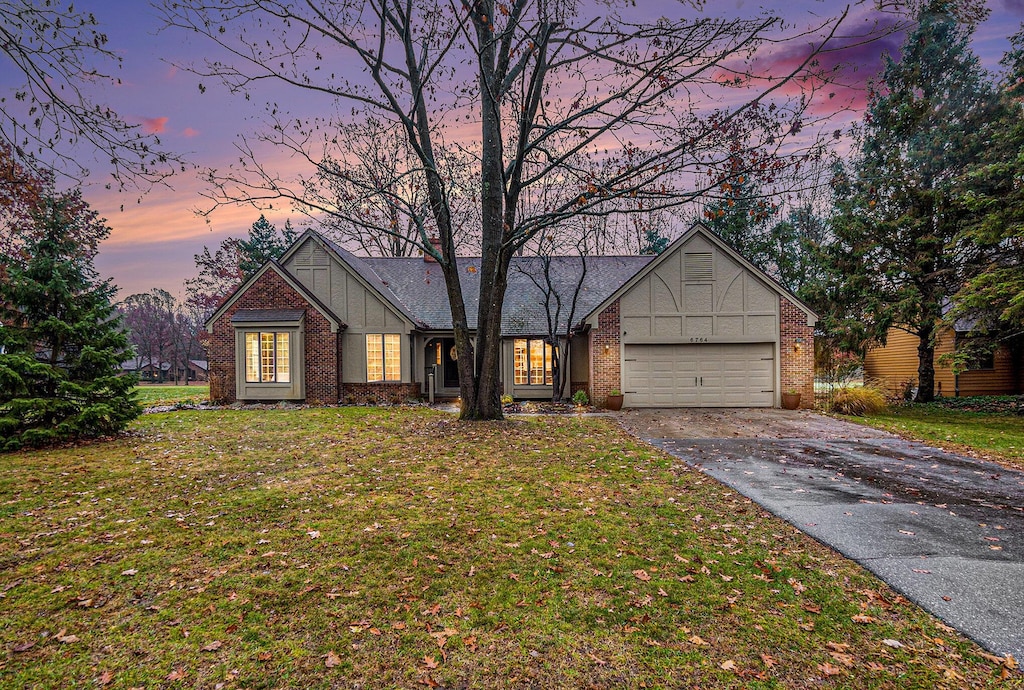 6764 Beechnut Ct, Canadian Lakes, MI 49346 - view of front facade featuring an attached garage, a yard, concrete driveway, and brick siding