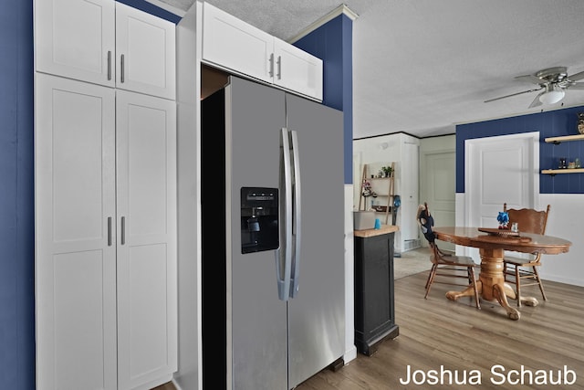 kitchen featuring a textured ceiling, stainless steel refrigerator with ice dispenser, light wood-style flooring, and white cabinets