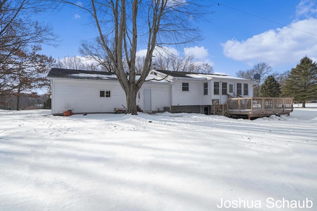 snow covered back of property with a deck