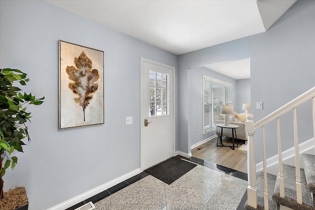 foyer with granite finish floor, baseboards, and stairs