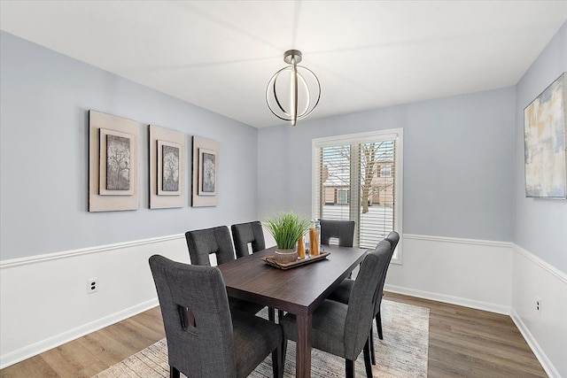 dining space featuring a notable chandelier, baseboards, and wood finished floors