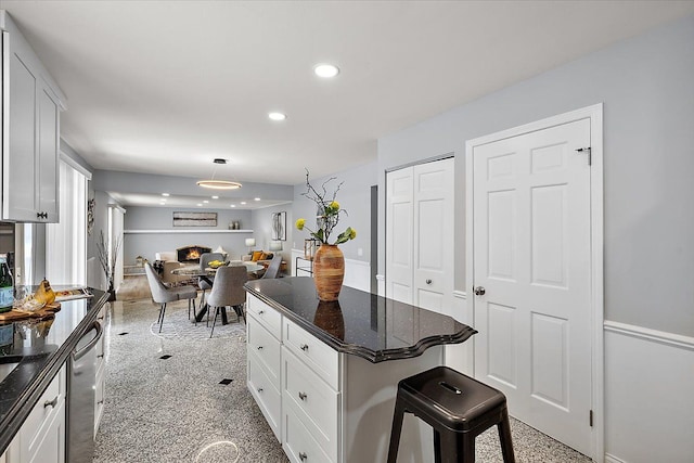 kitchen featuring a kitchen bar, recessed lighting, white cabinets, and stainless steel dishwasher