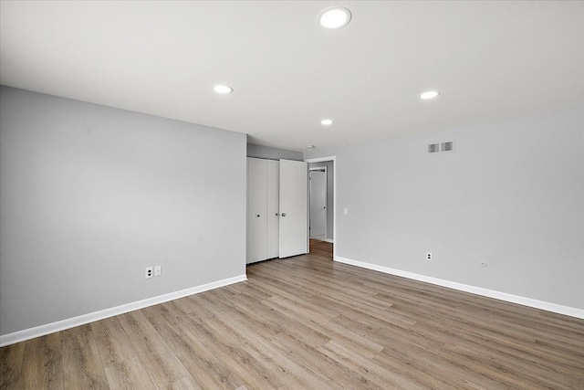 empty room featuring baseboards, visible vents, wood finished floors, and recessed lighting