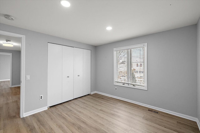 unfurnished bedroom featuring recessed lighting, a closet, visible vents, wood finished floors, and baseboards