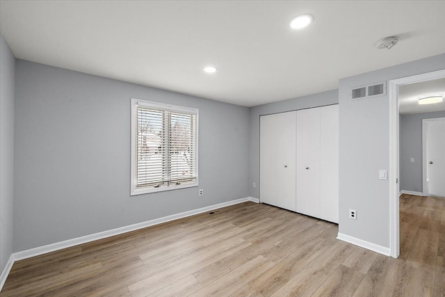 unfurnished bedroom featuring recessed lighting, wood finished floors, visible vents, baseboards, and a closet