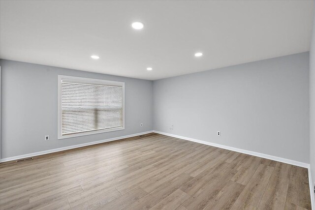 spare room featuring baseboards, wood finished floors, and recessed lighting