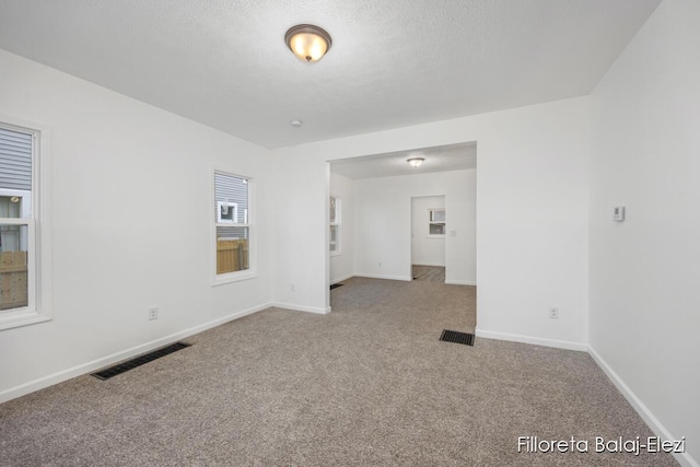 spare room with carpet flooring, visible vents, and baseboards