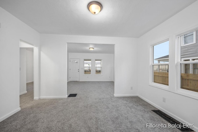 empty room with carpet floors, visible vents, and baseboards