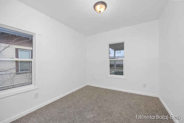 carpeted empty room featuring baseboards