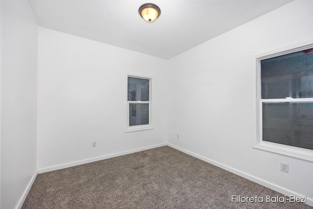 carpeted empty room featuring baseboards