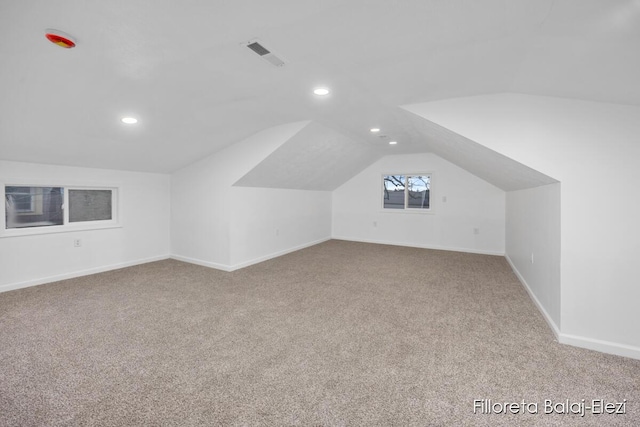 additional living space with lofted ceiling, carpet flooring, and visible vents