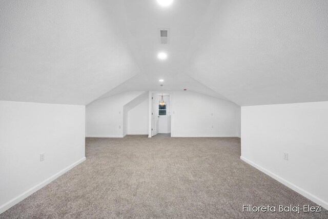 bonus room with carpet flooring, vaulted ceiling, a textured ceiling, and baseboards