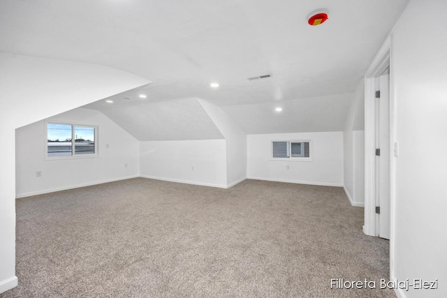 additional living space featuring carpet, visible vents, vaulted ceiling, and baseboards