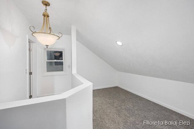 interior space with carpet flooring, vaulted ceiling, and baseboards