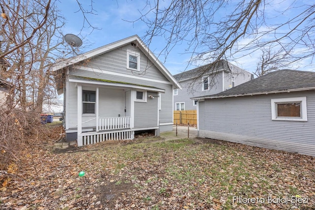 rear view of property with covered porch and fence