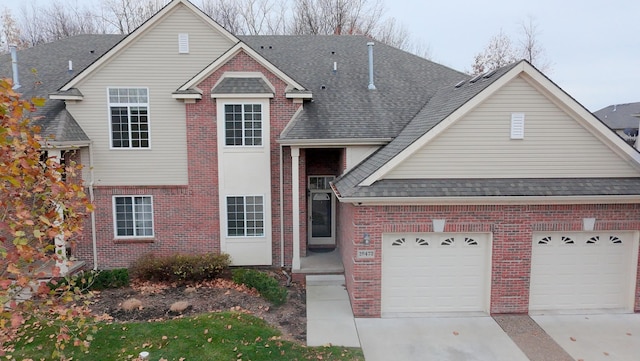 traditional-style house featuring brick siding, driveway, an attached garage, and roof with shingles