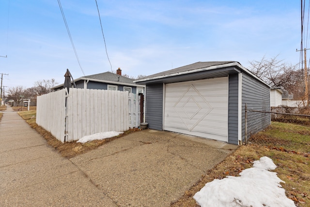 detached garage with concrete driveway and fence