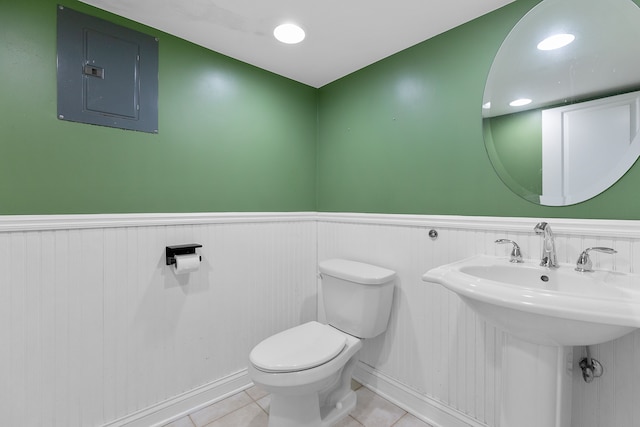 bathroom with toilet, a wainscoted wall, electric panel, and tile patterned floors