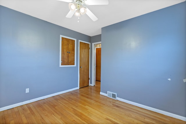 empty room featuring a ceiling fan, baseboards, visible vents, and wood finished floors