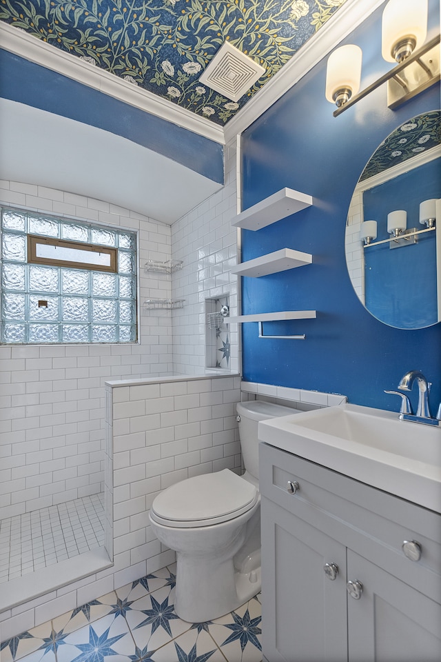 bathroom featuring visible vents, tiled shower, vanity, and toilet