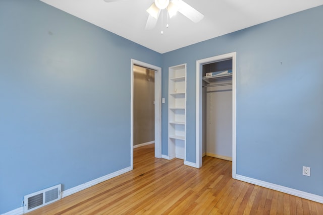 unfurnished bedroom featuring baseboards, visible vents, a ceiling fan, wood finished floors, and a closet