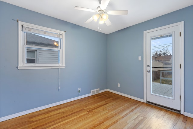 spare room with baseboards, visible vents, ceiling fan, and wood finished floors