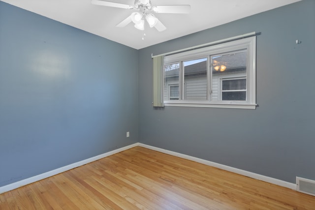 empty room with a ceiling fan, visible vents, baseboards, and wood finished floors