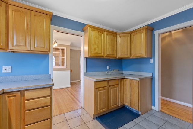 kitchen with ornamental molding, light countertops, baseboards, and light tile patterned flooring