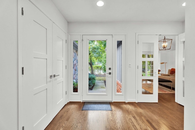 doorway featuring plenty of natural light, wood finished floors, and an inviting chandelier