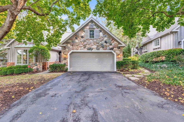 view of front of property with a garage, stone siding, board and batten siding, and driveway