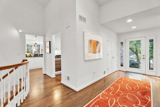 foyer entrance with recessed lighting, a high ceiling, wood finished floors, visible vents, and baseboards