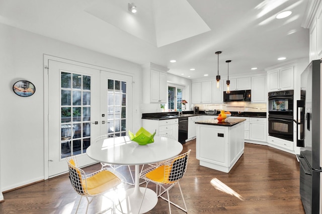 kitchen with dark countertops, white cabinets, a kitchen island, and black appliances