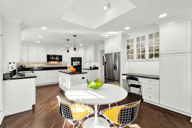 kitchen with built in desk, dark countertops, dark wood-type flooring, white cabinetry, and black appliances