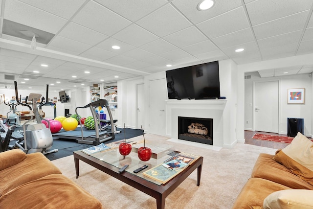 carpeted living area with a fireplace with flush hearth, baseboards, a drop ceiling, and recessed lighting