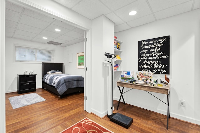 bedroom with a paneled ceiling, recessed lighting, baseboards, and wood finished floors