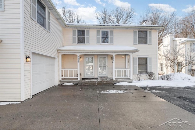 view of front facade featuring driveway, covered porch, a garage, and a chimney