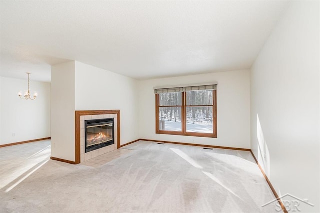 unfurnished living room with a fireplace, visible vents, baseboards, carpet, and an inviting chandelier