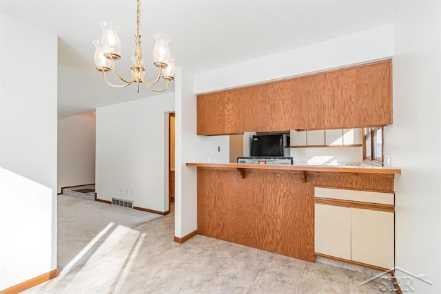 kitchen featuring baseboards, visible vents, decorative light fixtures, an inviting chandelier, and black fridge