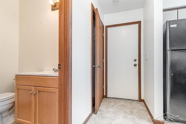 bathroom with vanity, toilet, and baseboards