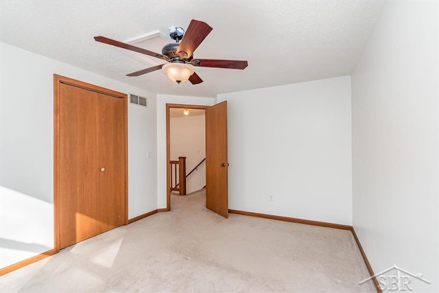 unfurnished bedroom featuring light carpet, a ceiling fan, visible vents, baseboards, and a closet